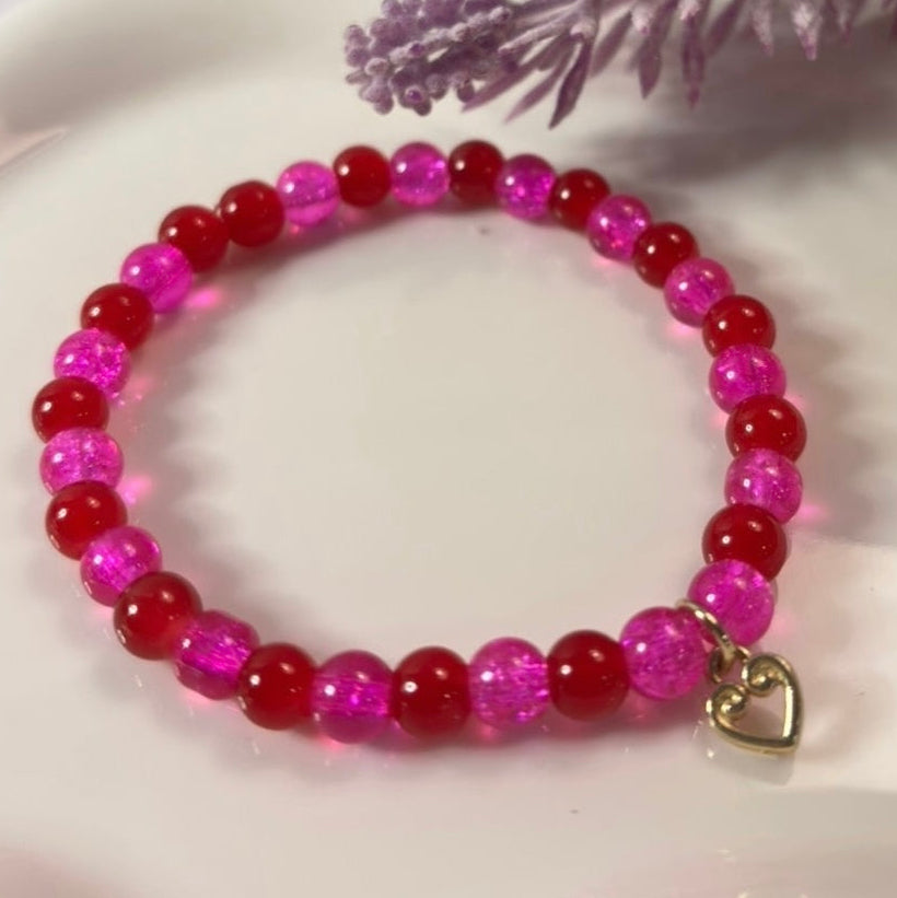 Handmade pink and red stretch bracelet with gold heart charm detail