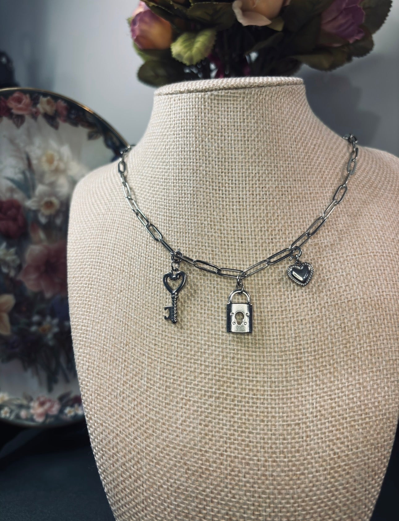 Necklace with charms on a mannequin bust against a floral background